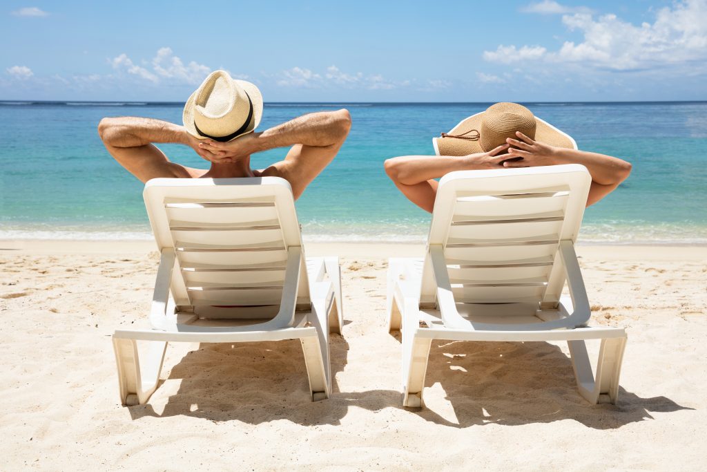 Young Couple Relaxing On Deck Chair At Beach